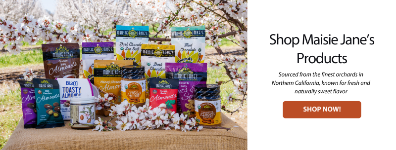 Maisie Janes Almond products in an orchard with blooms-Shop Maisie Jane's Products-click the button