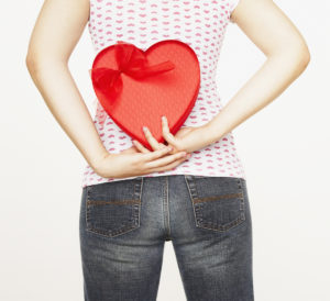 women holding heart shaped box behind back