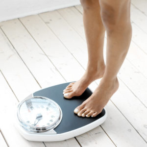 woman standing on tip toes on a weighing scale