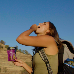 Woman hiking and stoping to eat out of her Maisie Jane's snack packs